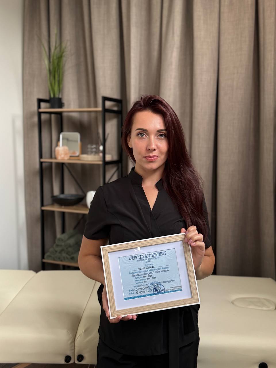 De masseuse in de behandelruimte, met een ingelijst certificaat in haar handen