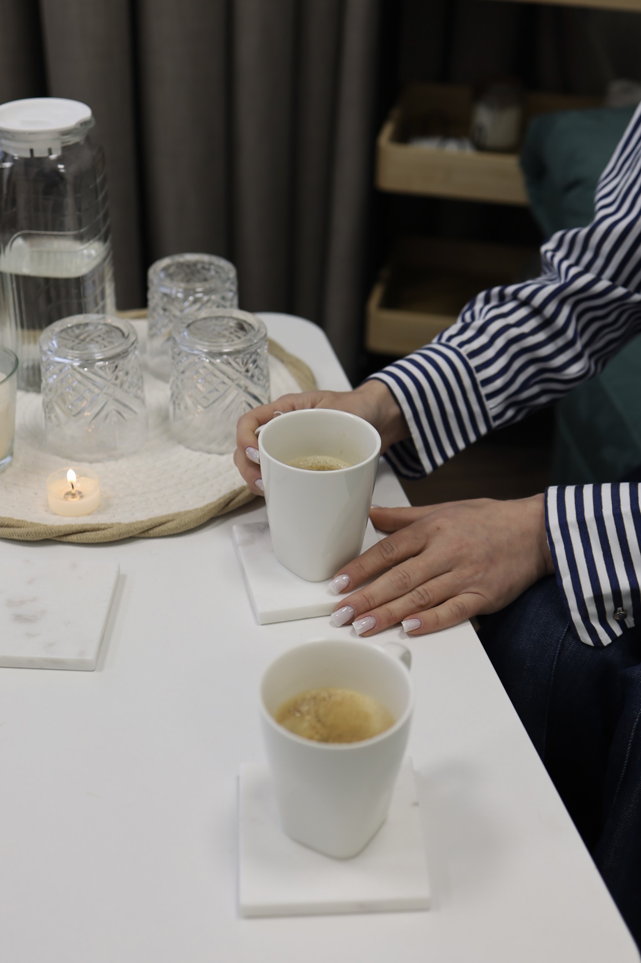 Twee kopjes thee en een kaarsje op een witte tafel